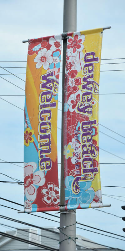 A close-up of colorful Dewey beach welcome banner hanging on a post.