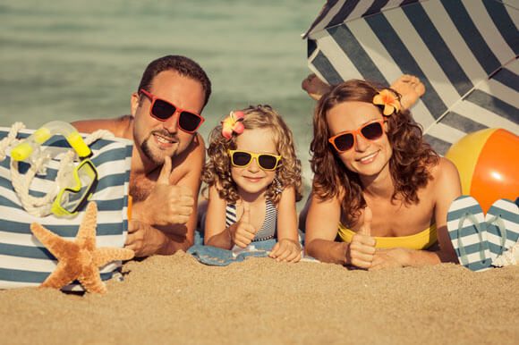 A close up of Happy family enjoying the sun and sandy beach.